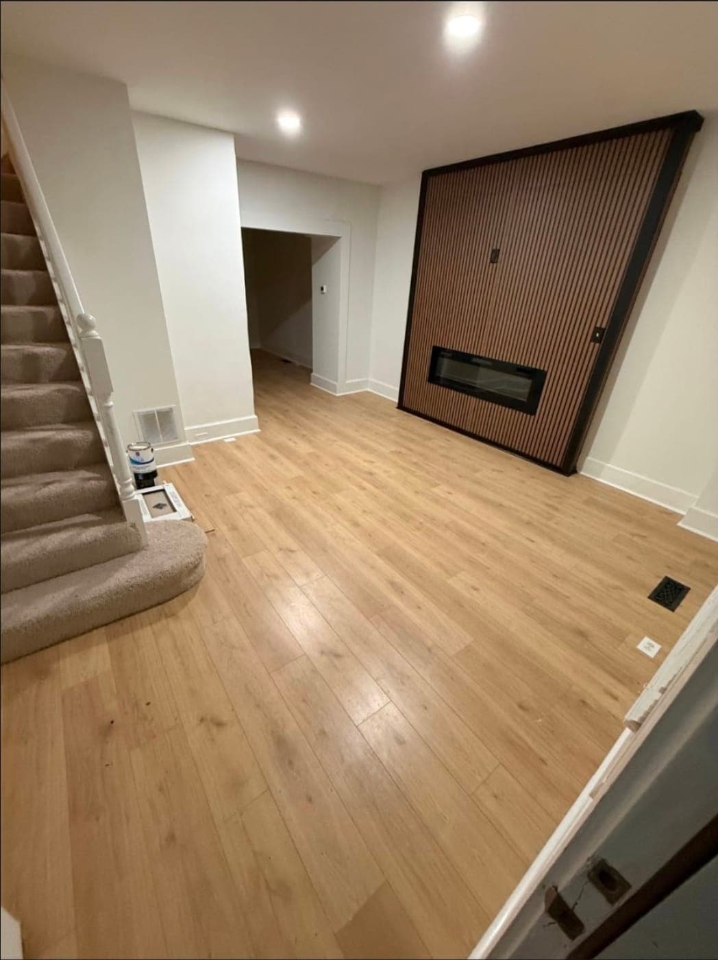 Basement finished by Elite Finishes with new flooring, fresh paint and a slat wall fireplace