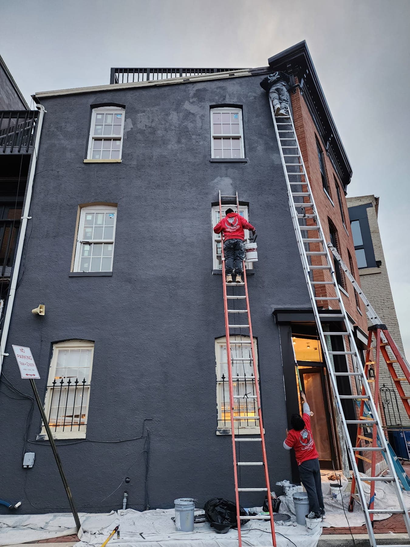 Elite Finishes crew on ladders painting a stucco rowhouse exterior