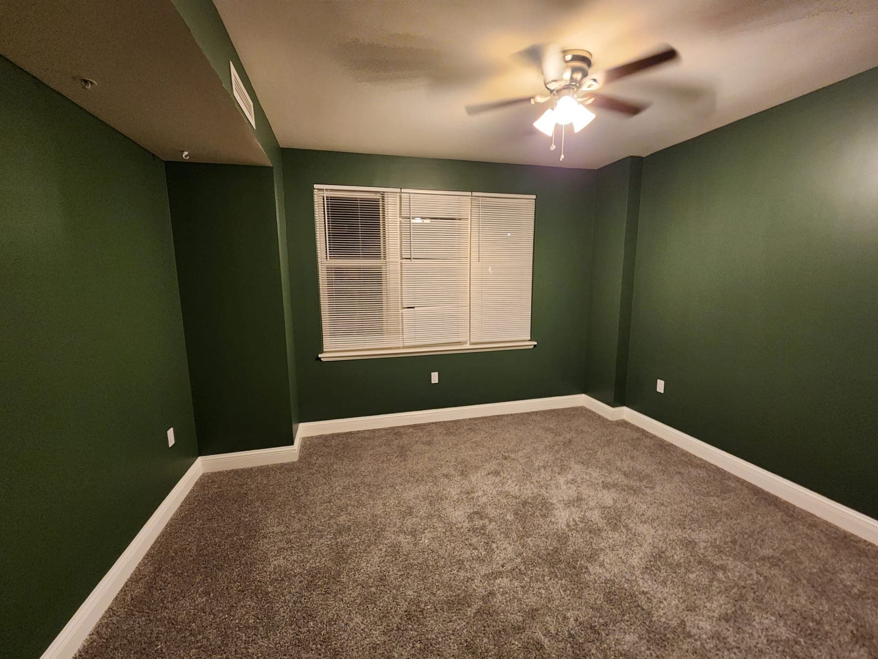 Bedroom painted forest green with white baseboards by Elite Finishes