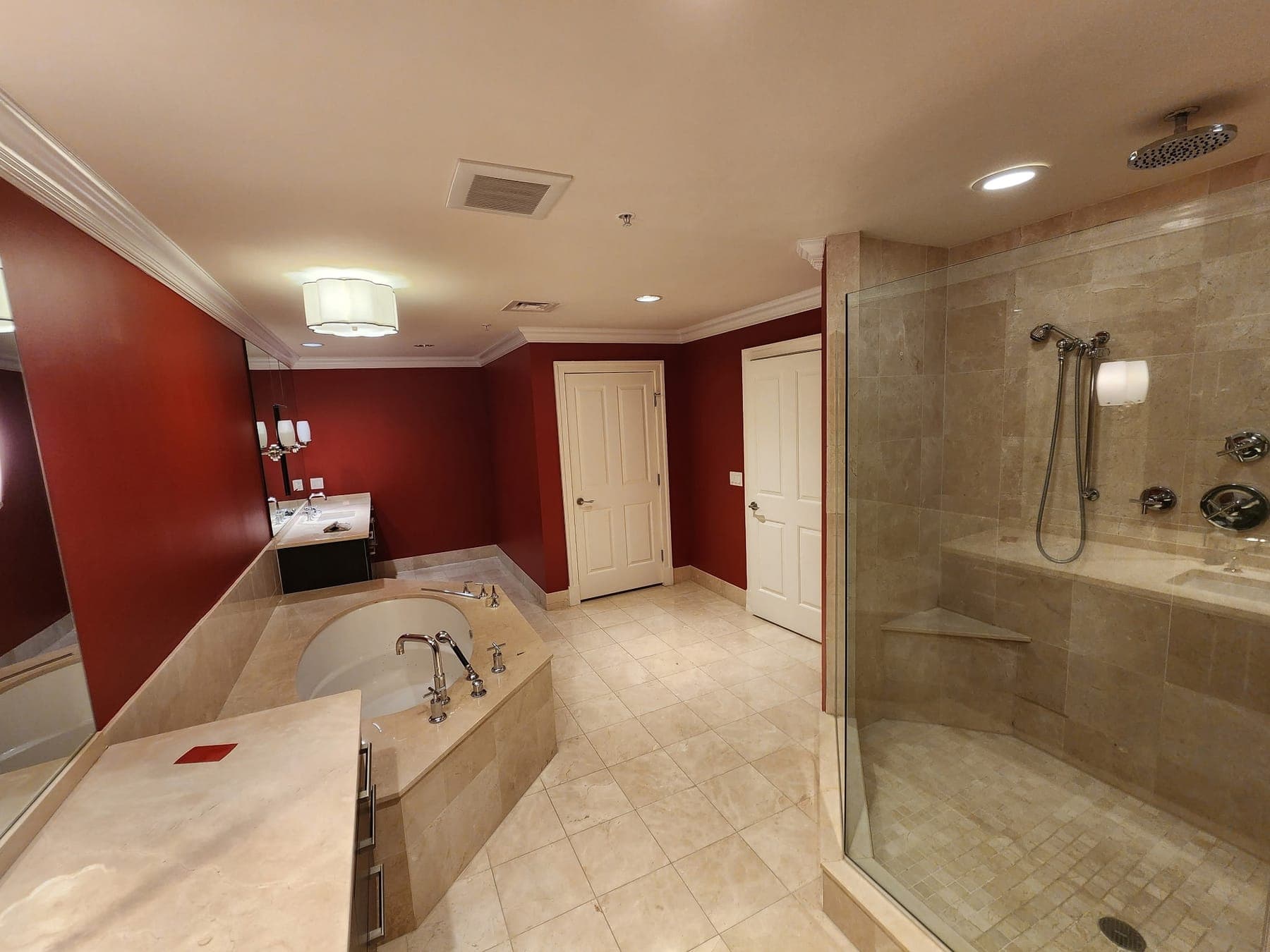 Primary bathroom with red walls, soaking tub and marble walk-in shower by Elite Finishes